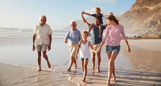 Family walking together along a beach beneath coastal cliffs