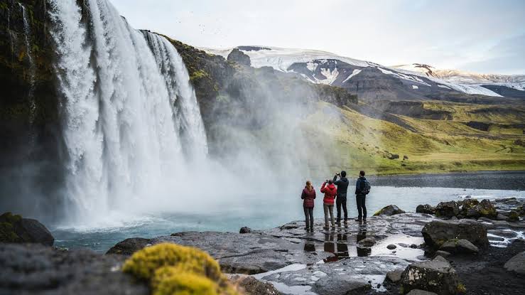 Visitors standing beside a powerful waterfall