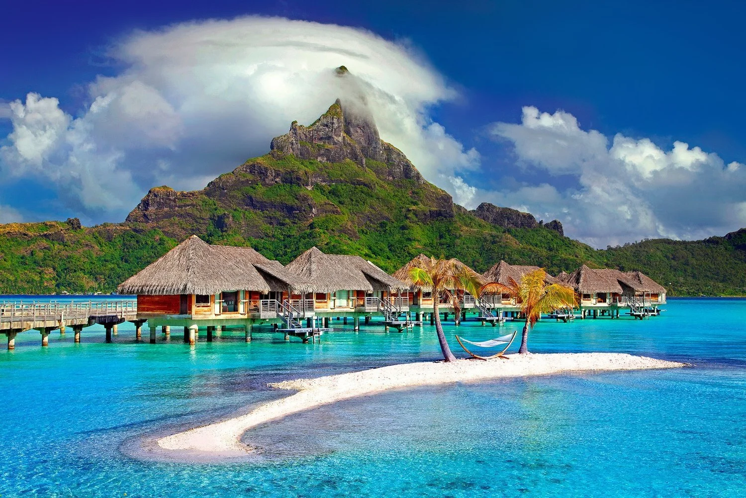 Overwater villas beneath a steep tropical island mountain