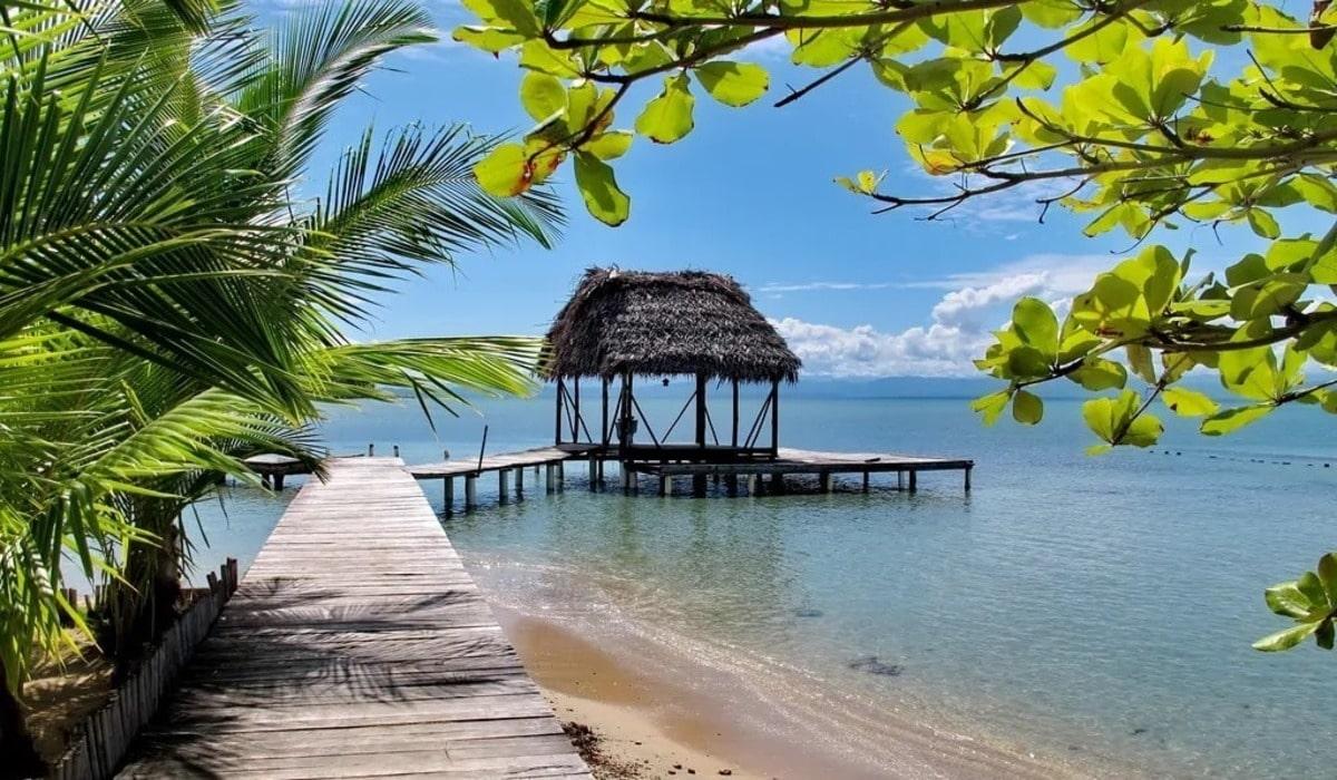 Wooden boardwalk leading to a thatched shelter over turquoise water